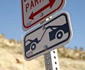 Tow-away zone sign with two arrows and a depiction of a tow truck; blue and white.