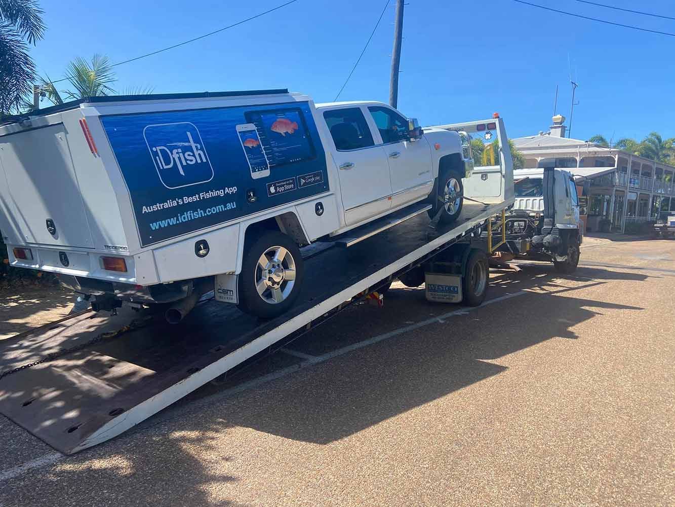 A White Truck is Being Towed Down a Ramp by a Tow Truck — Cape York Towing & Transport in Lockhart River, QLD