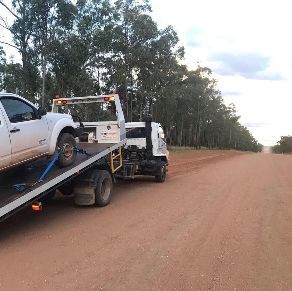 A White Truck is Being Towed by a Tow Truck on a Dirt Road — Cape York Towing & Transport in Archer River, QLD