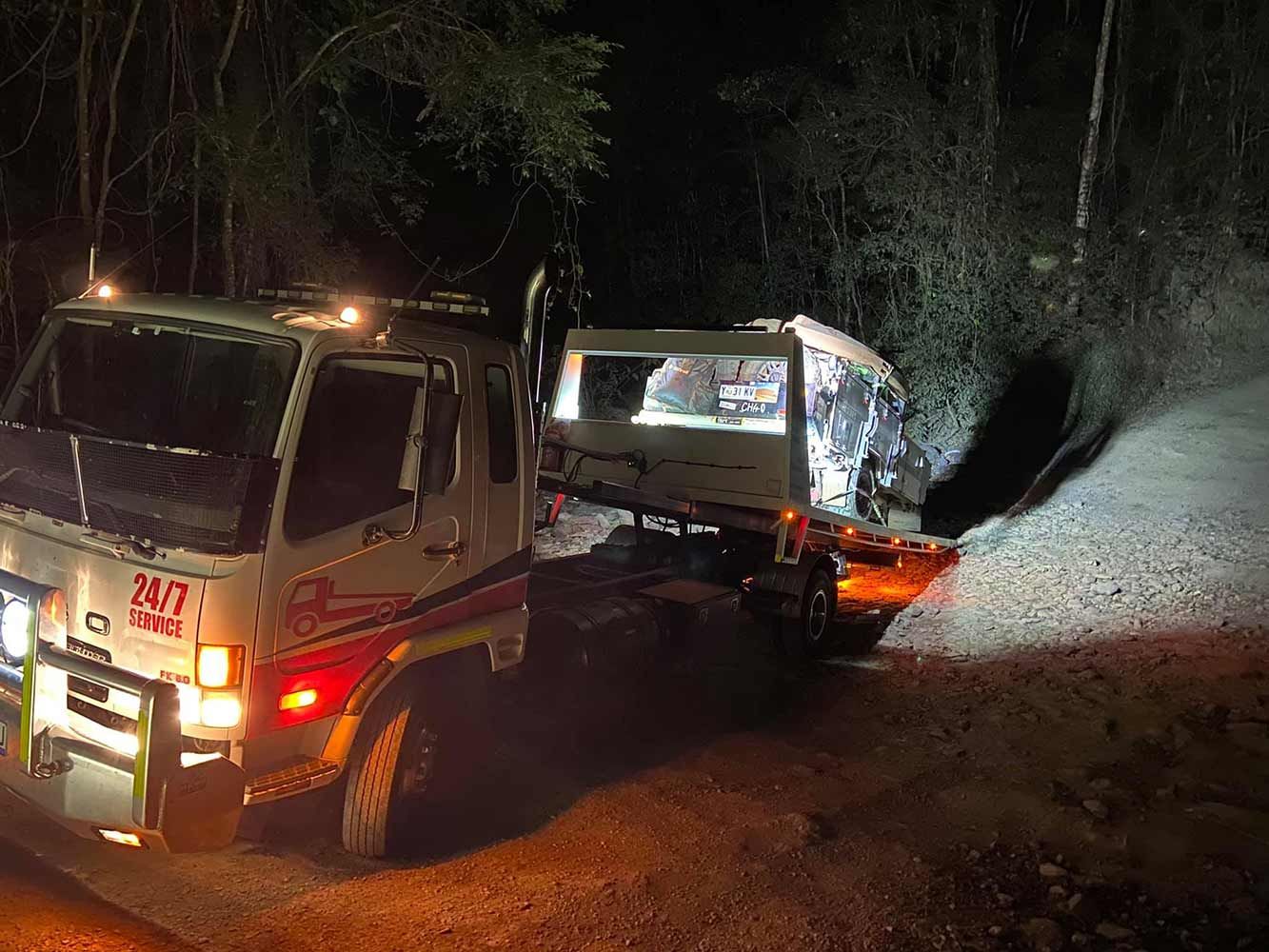 A Tow Truck is Driving Down a Dirt Road at Night — Cape York Towing & Transport in Bramwell, QLD
