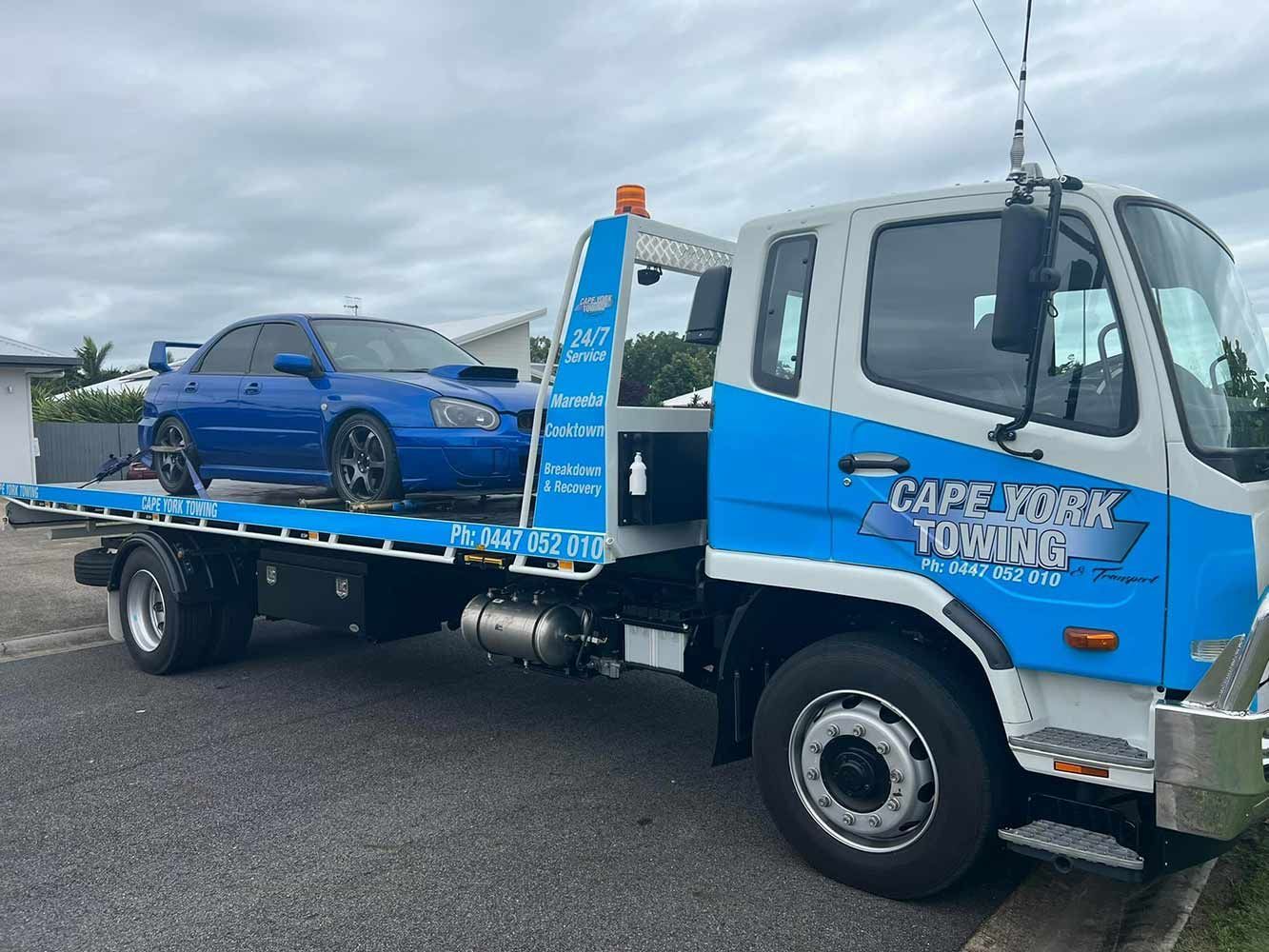 Blue tow truck carrying a blue car parked roadside — Cape York Towing in Georgetown, QLD