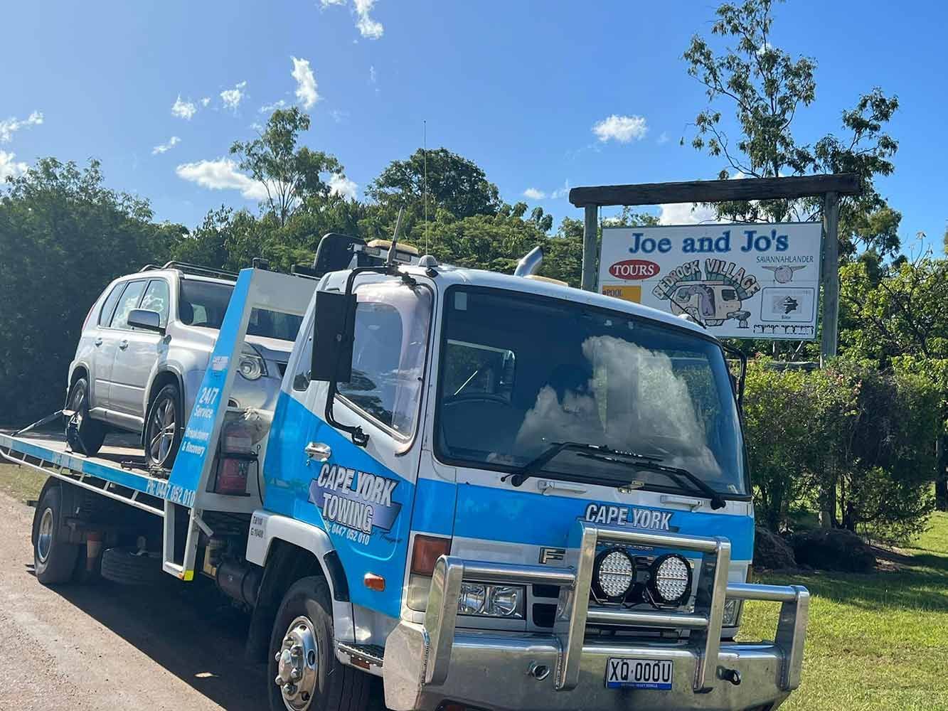 A Tow Truck With a Car on the Back is Parked on the Side of the Road — Cape York Towing & Transport in Bramwell, QLD