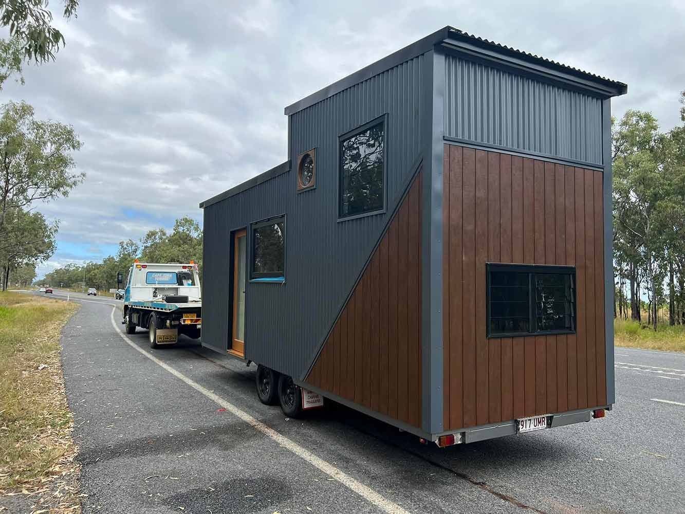A Tiny House is Being Towed Down a Road by a Tow Truck — Cape York Towing & Transport in Sunshine Coast, QLD