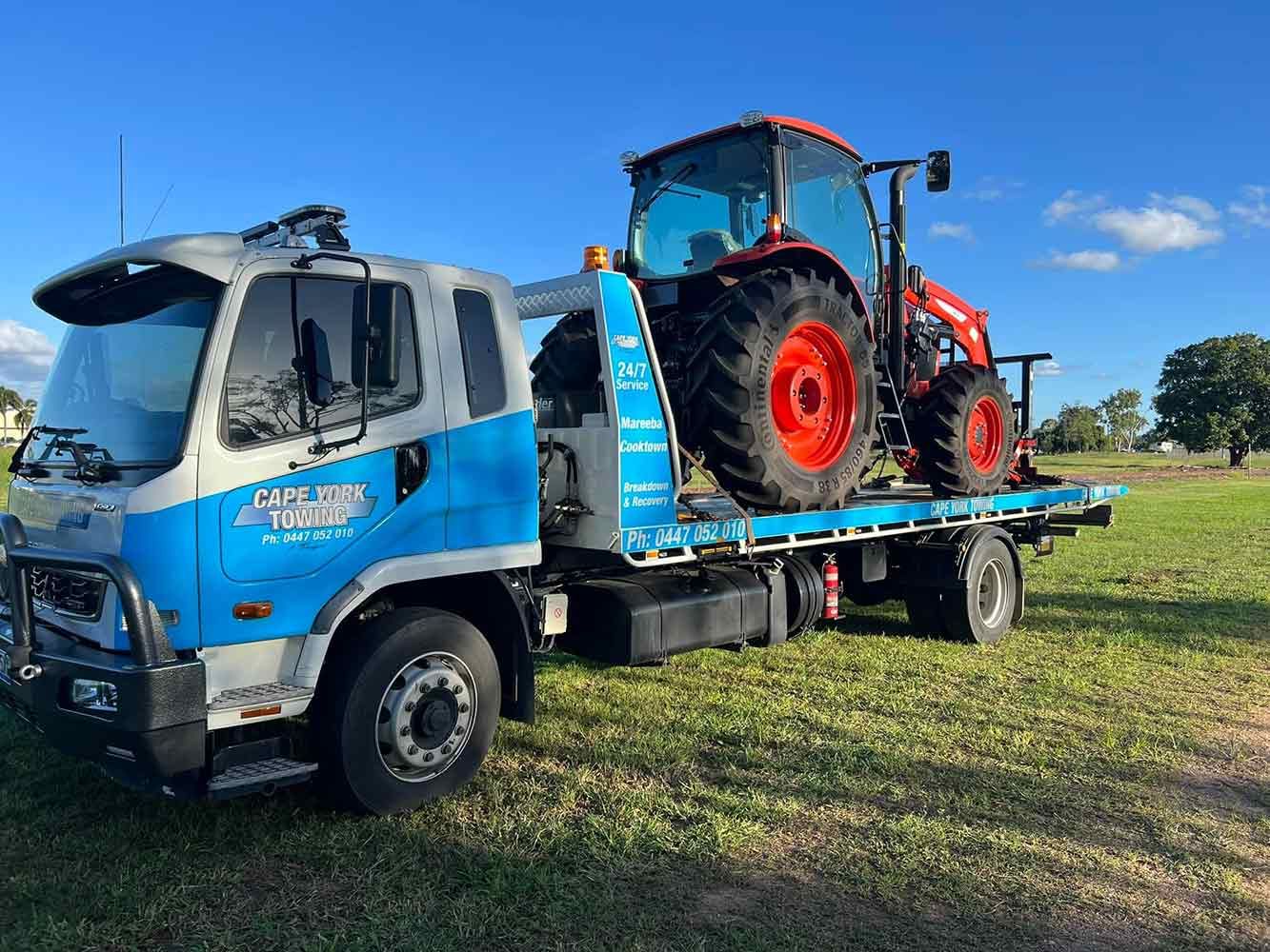 A Tow Truck is Towing a Tractor in a Field — Cape York Towing & Transport in Normanton, QLD