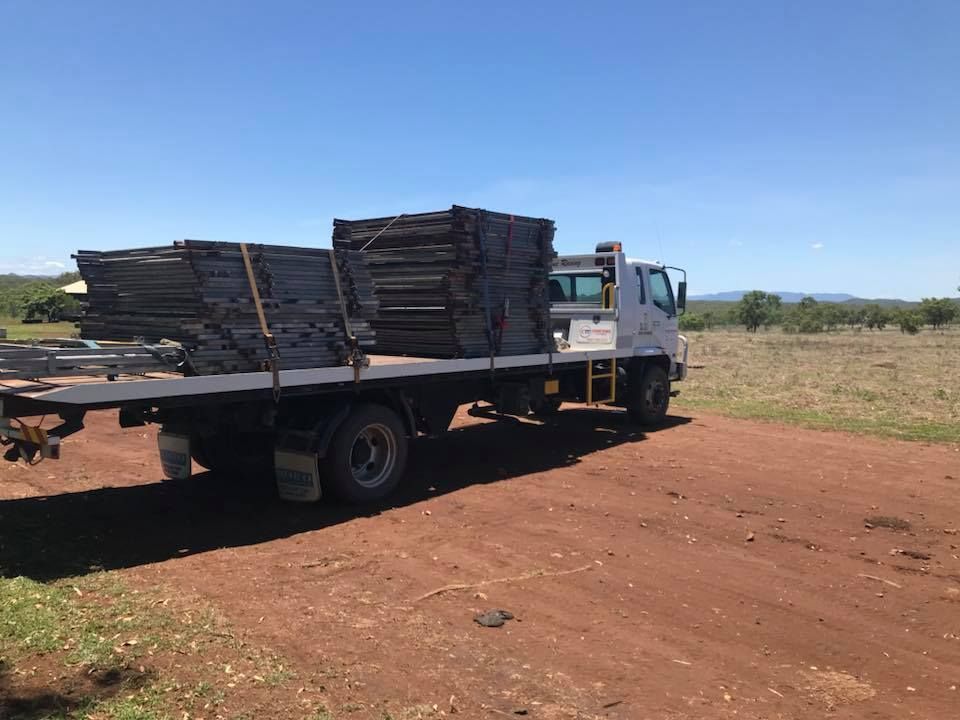A Tow Truck With Two Cars on the Back is Parked in a Dirt Lot — Cape York Towing & Transport in Archer River, QLD