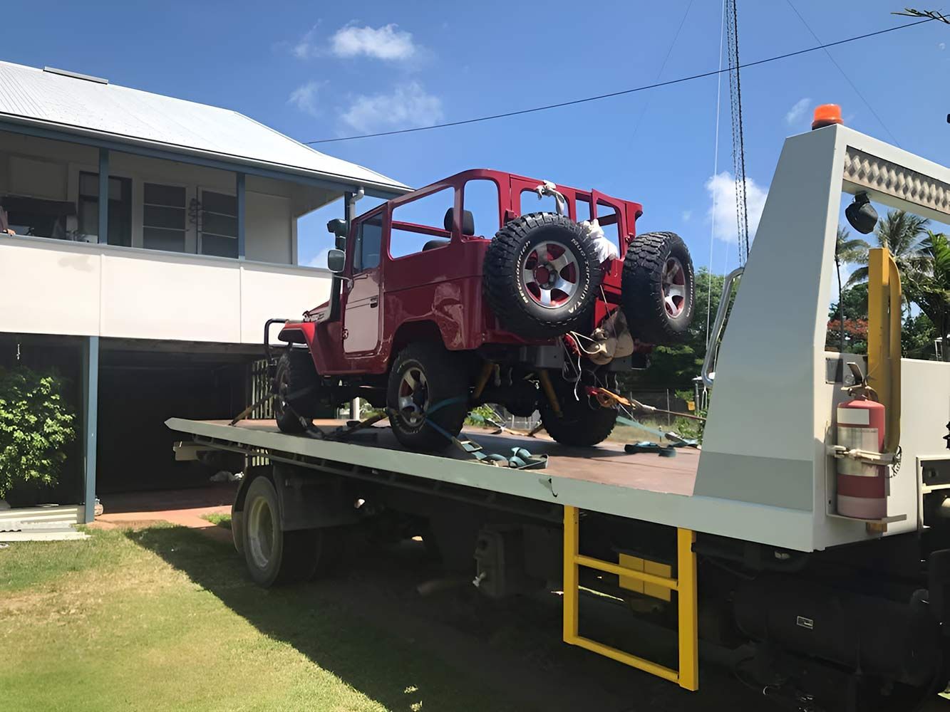 A Red Jeep is Sitting on Top of a Flatbed Tow Truck — Cape York Towing & Transport in Bamaga, QLD