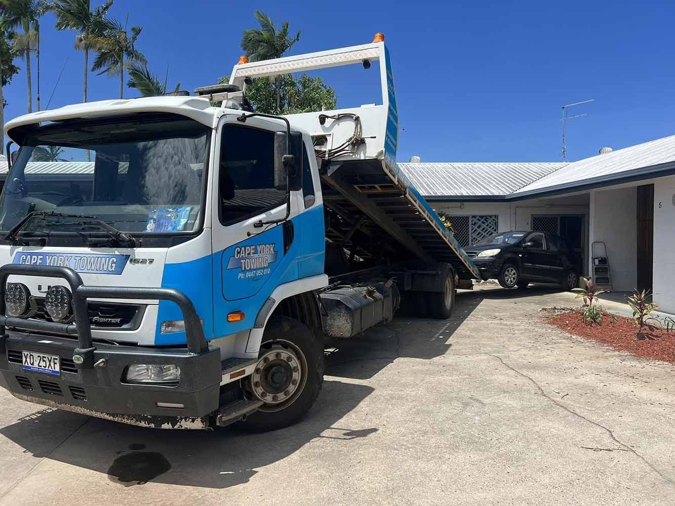 A Blue and White Tow Truck is Parked in Front of a House — Cape York Towing & Transport in Coen, QLD