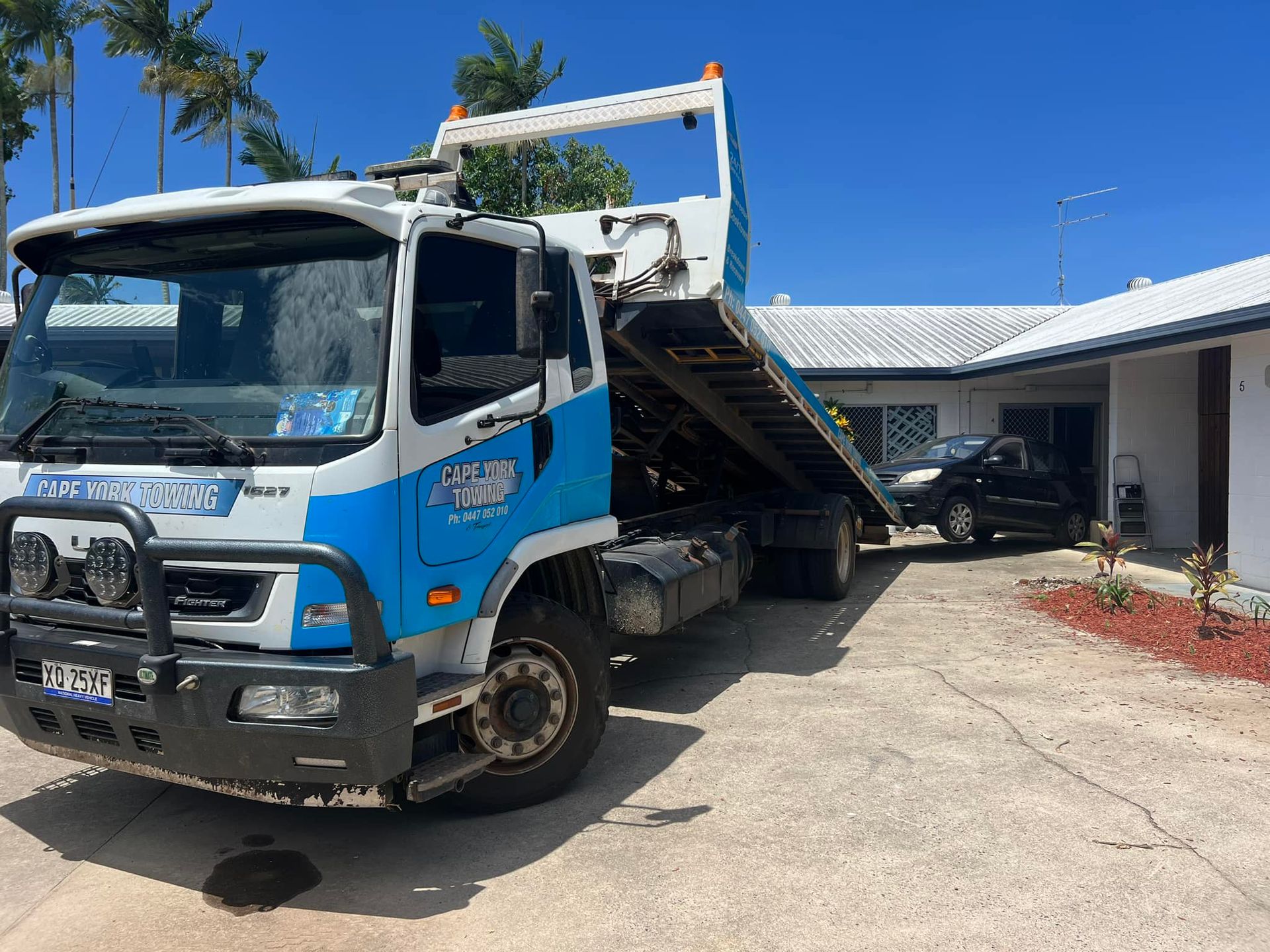 A Tow Truck is Driving Down a Dirt Road at Night — Cape York Towing & Transport in Townsville, QLD