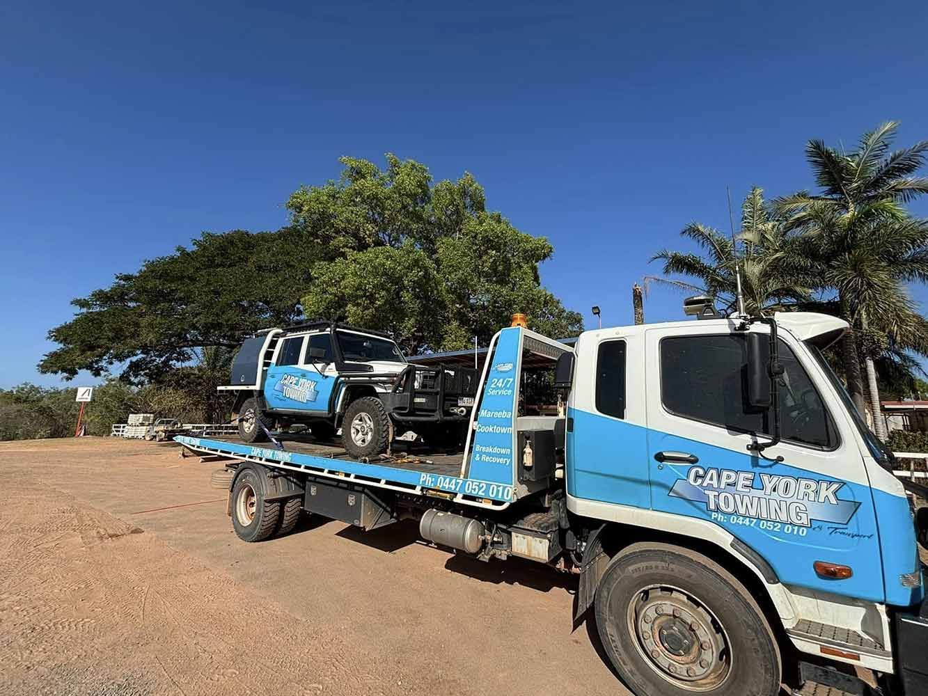 A Tow Truck With Two Cars on the Back is Parked in a Dirt Lot — Cape York Towing & Transport in Karumba, QLD