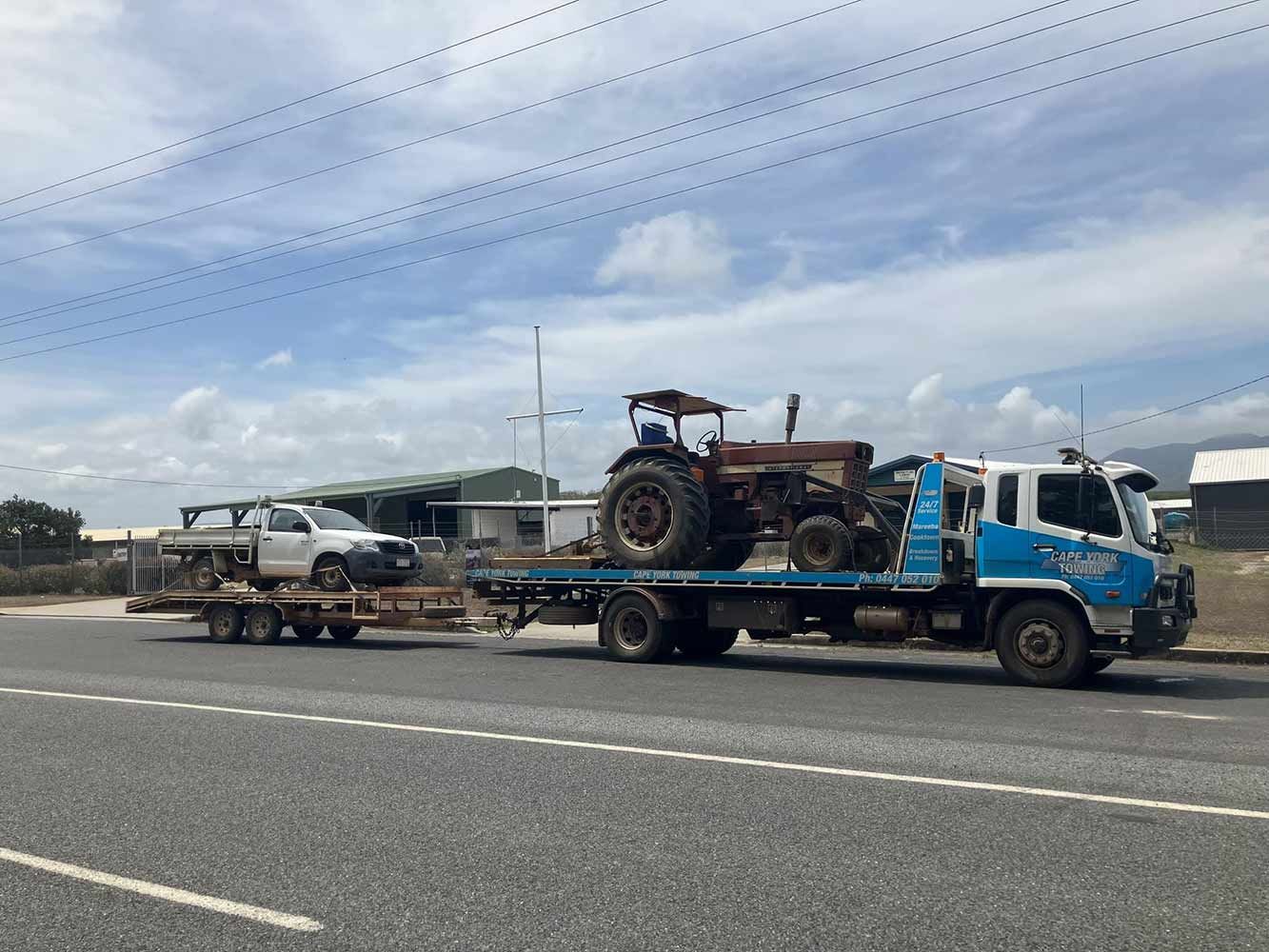 A Tow Truck is Carrying a Tractor and a Truck on a Trailer — Cape York Towing & Transport in Adelaide, SA