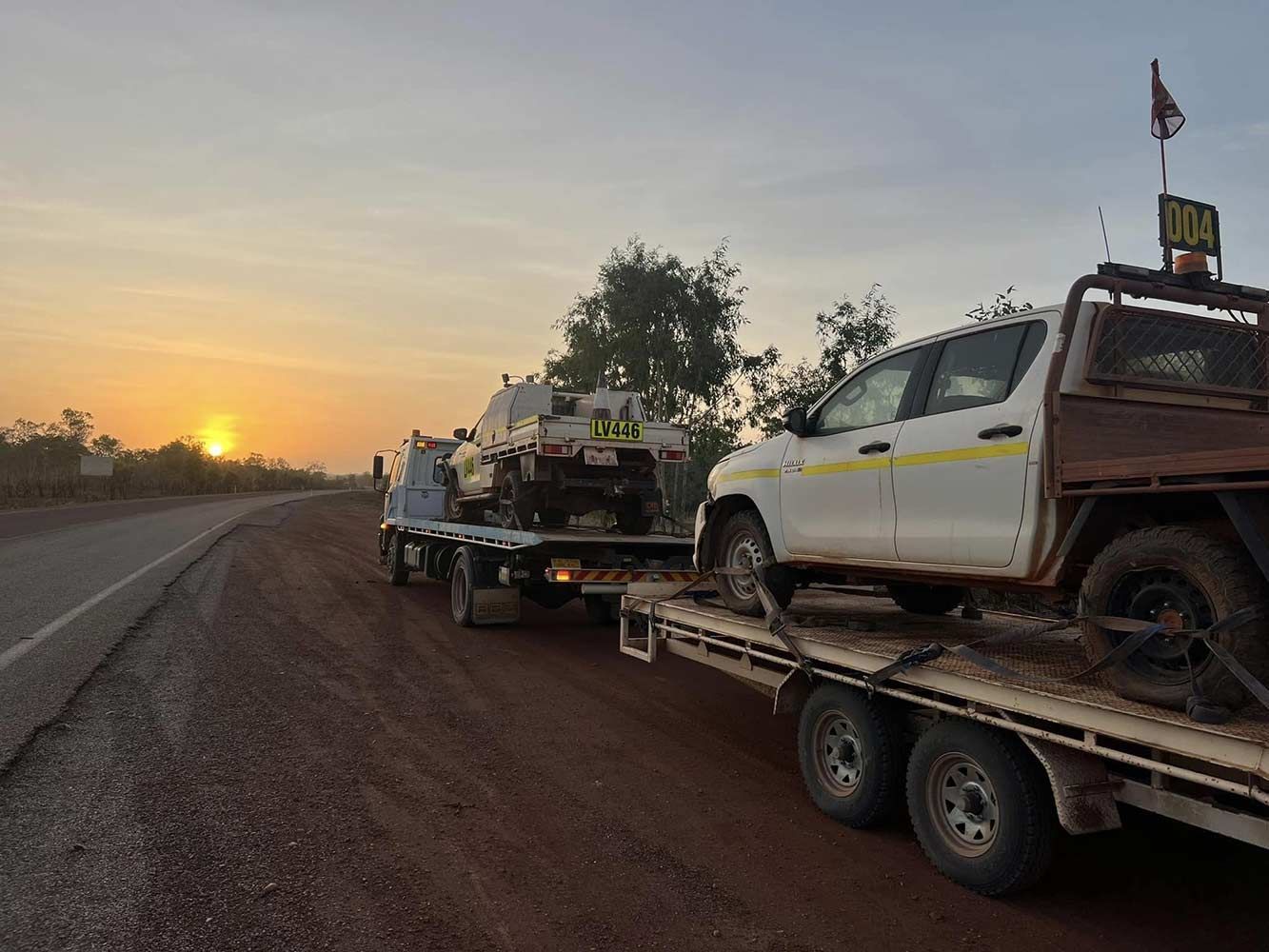 A White Truck is Being Towed Down a Dirt Road by a Tow Truck — Cape York Towing & Transport in Townsville, QLD