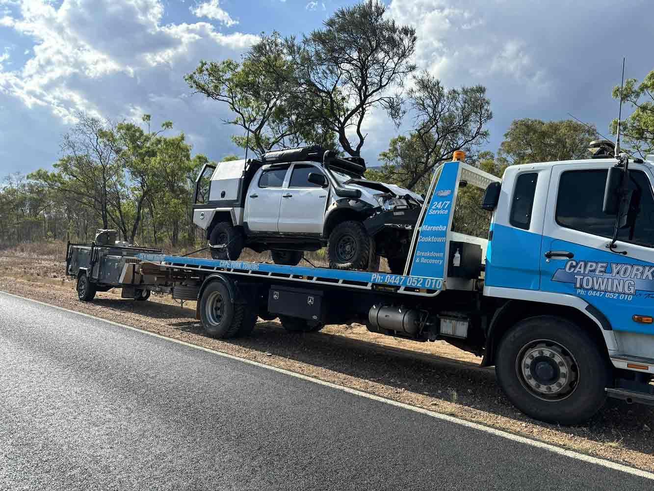 A White Truck is Being Towed by a Blue Tow Truck — Cape York Towing & Transport in Cooktown, QLD