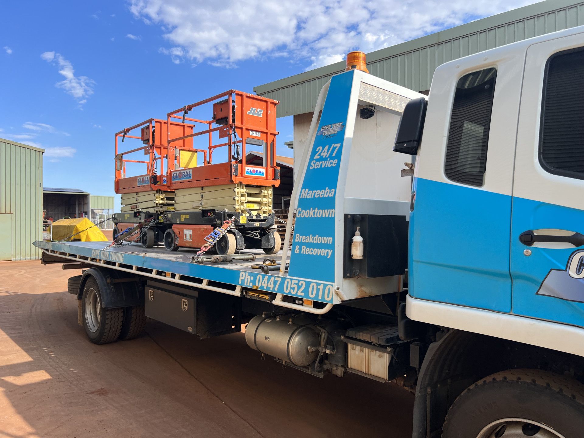 A Tow Truck With a Car on the Back is Parked on the Side of the Road — Cape York Towing & Transport in Kowanyama, QLD