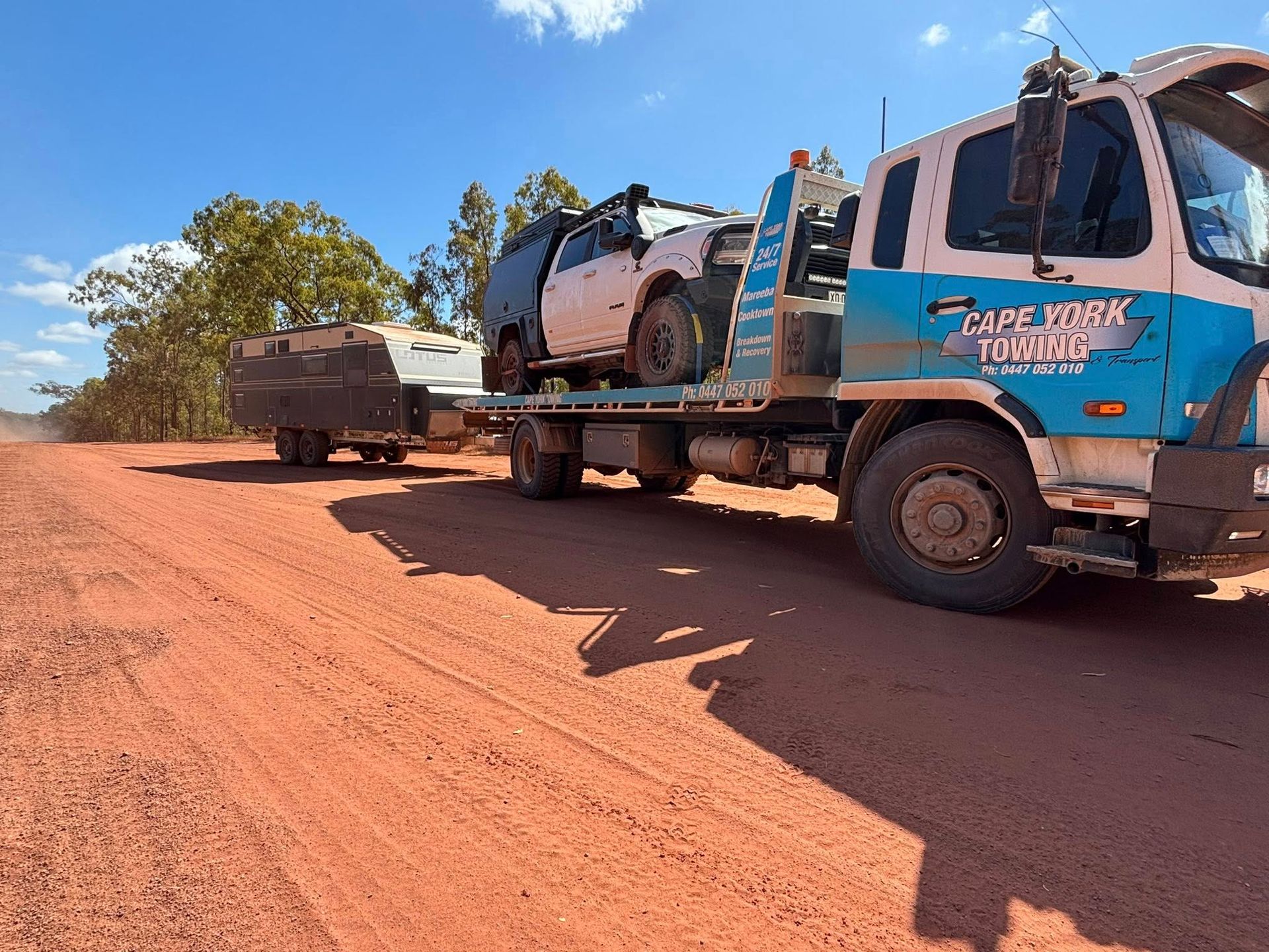 Tow Truck With White 4x4 and Trailer on Red Dirt Road Under a Blue Sky — Cape York Towing & Transport in Cairns, QLD
