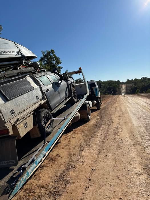 Truck Being Towed on a Flatbed Truck on a Dirt Road Under a Blue Sky — Cape York Towing & Transport in Cairns, QLD