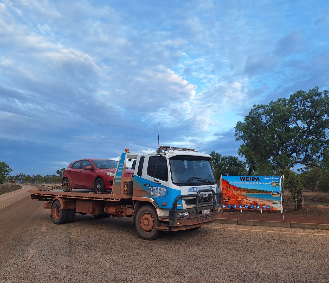 An Orange Car is Being Towed by a Tow Truck — Cape York Towing & Transport in Mount Molloy, QLD