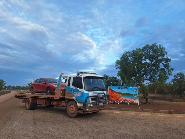A Tow Truck With a Red Car on the Back is Parked on a Dirt Road — Cape York Towing & Transport in Mareeba, QLD