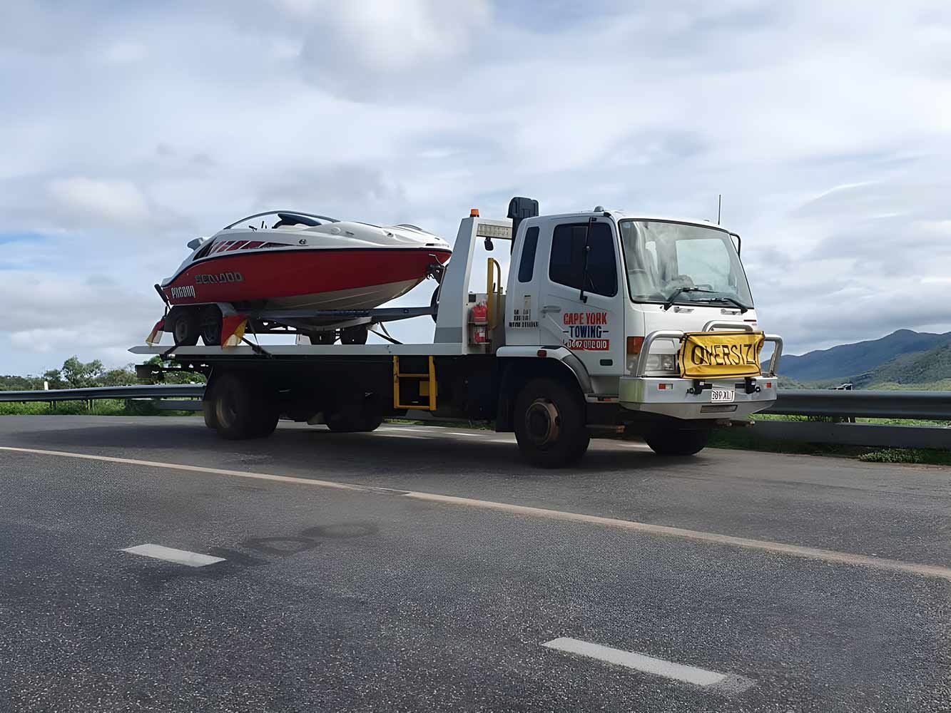 A Tow Truck is Carrying a Boat Down the Road — Cape York Towing & Transport in Mackay, QLD