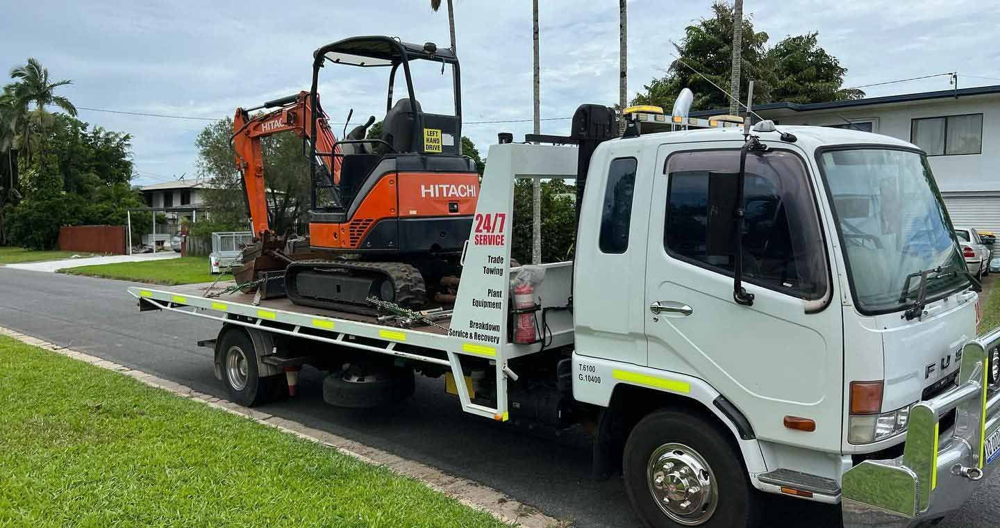A Tow Truck is Carrying a Small Excavator on the Back of It — Cape York Towing & Transport in Georgetown, QLD