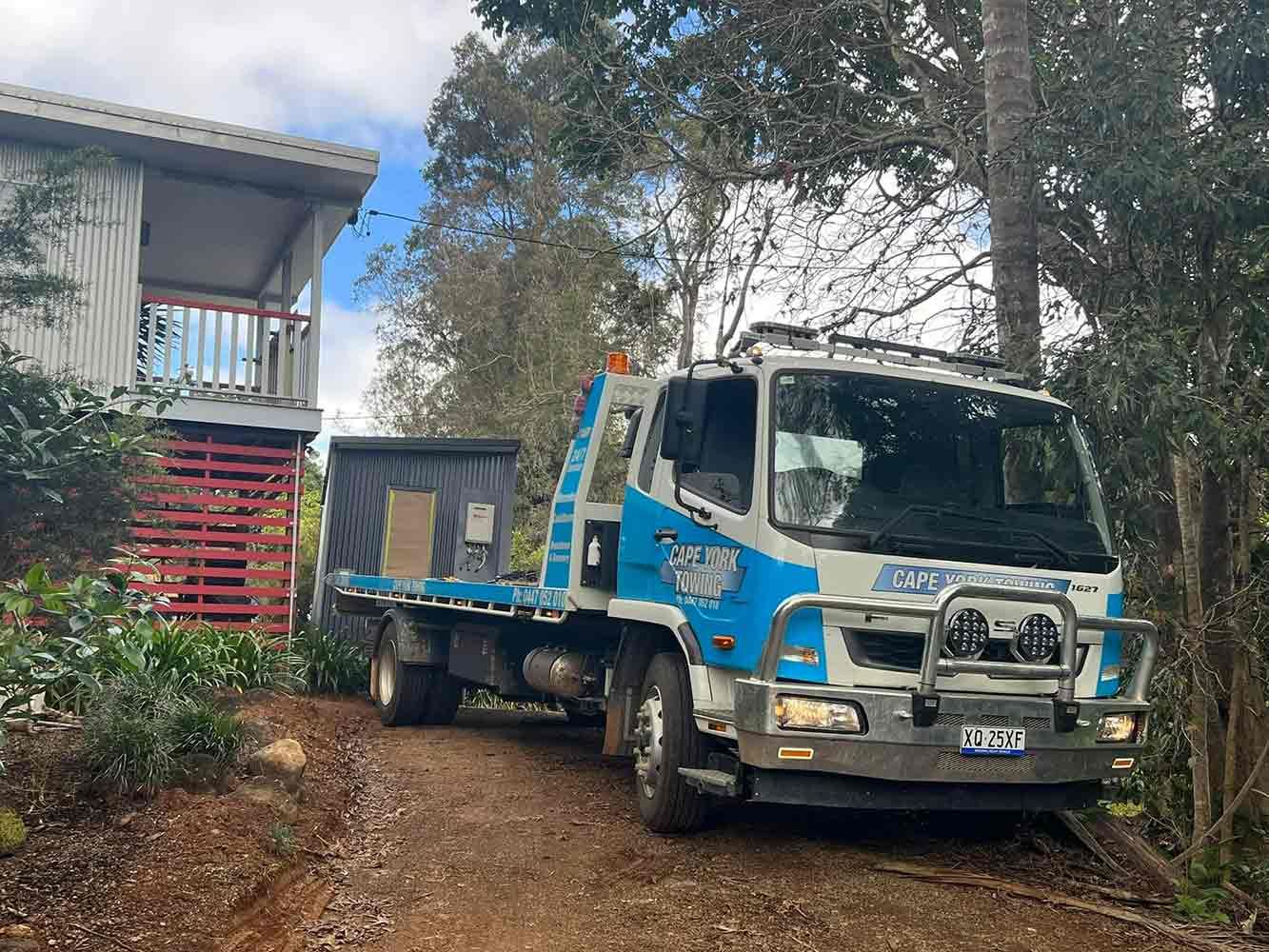 A Tow Truck is Parked in Front of a House on a Dirt Road — Cape York Towing & Transport in Ravenshoe, QLD