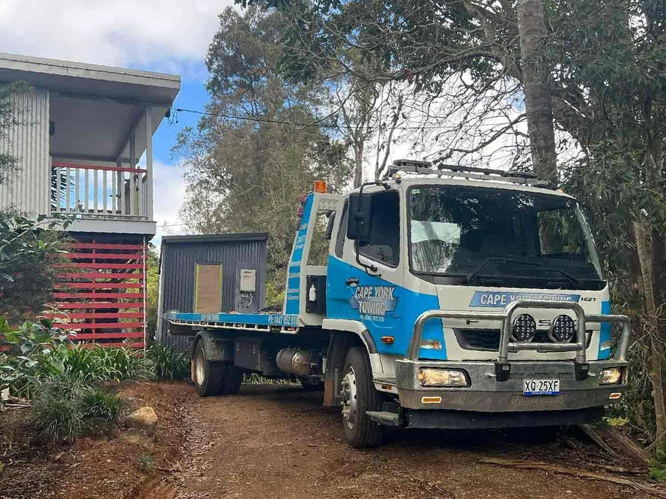 A Tow Truck is Carrying Two Trucks Down a Muddy Road — Cape York Towing & Transport in Adelaide, SA