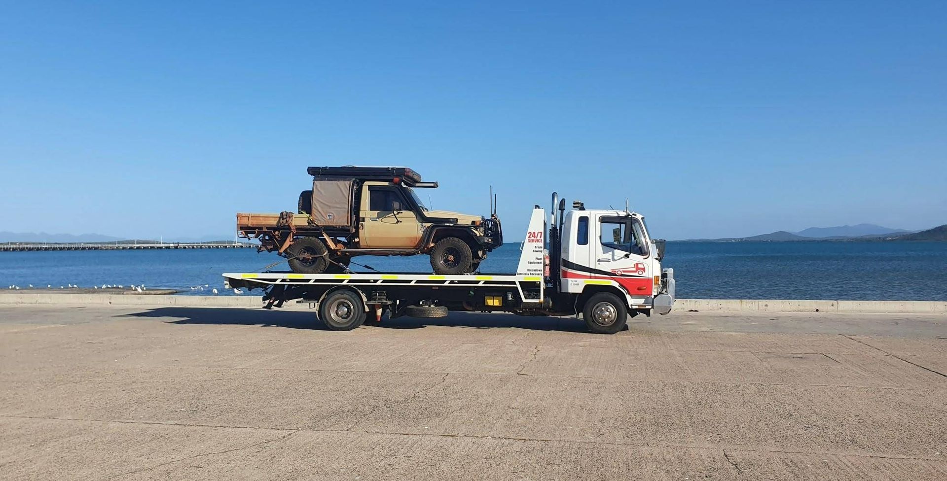 A Tow Truck is Carrying a Jeep on the Back of It on a Beach — Cape York Towing & Transport in Mackay, QLD