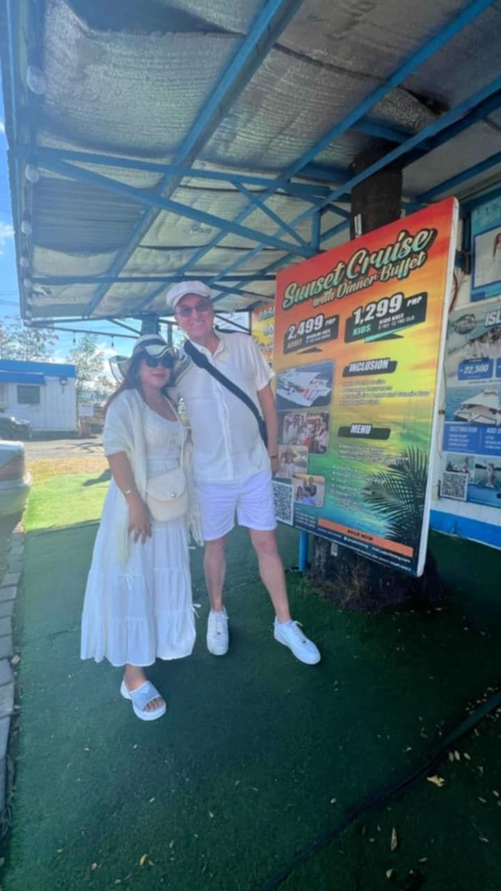 A man and a woman are standing next to each other in front of a sign.