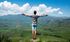 A man is standing on top of a mountain with his arms outstretched.