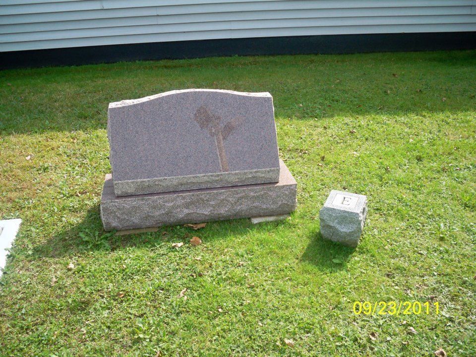 Headstone on grass, with a smaller stone next to it, a building background, dated September 28, 2011.