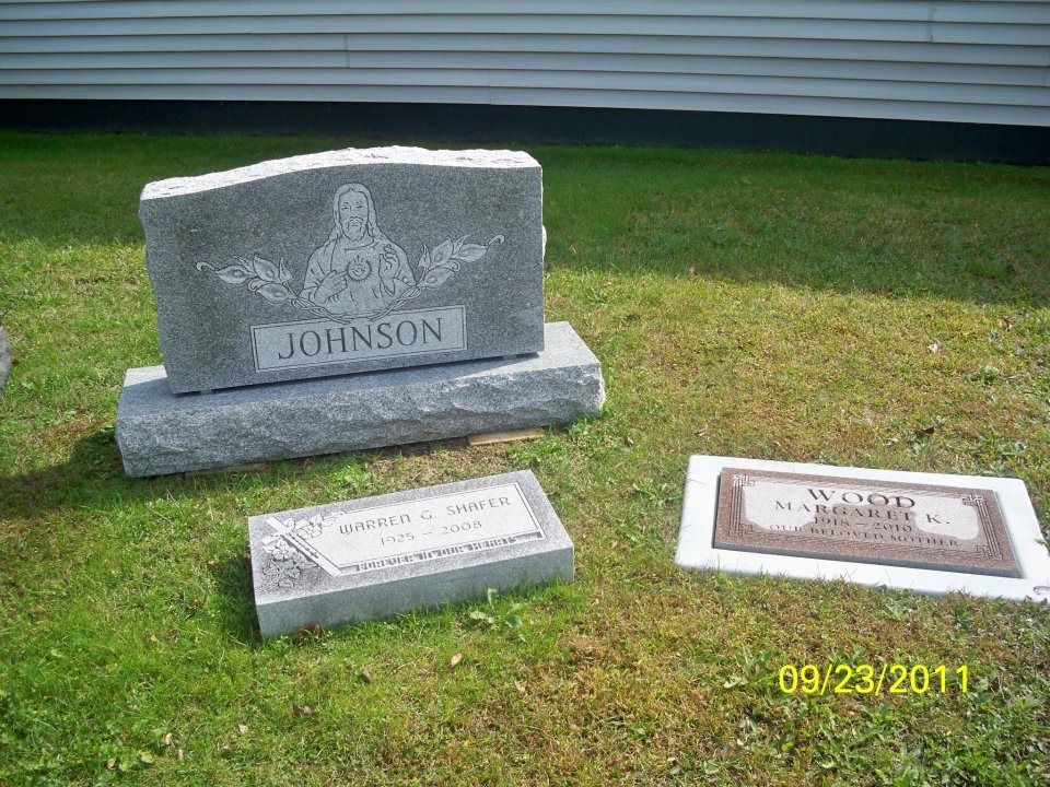 Gravestone with the last name Johnson, and two other grave markers on a green lawn.