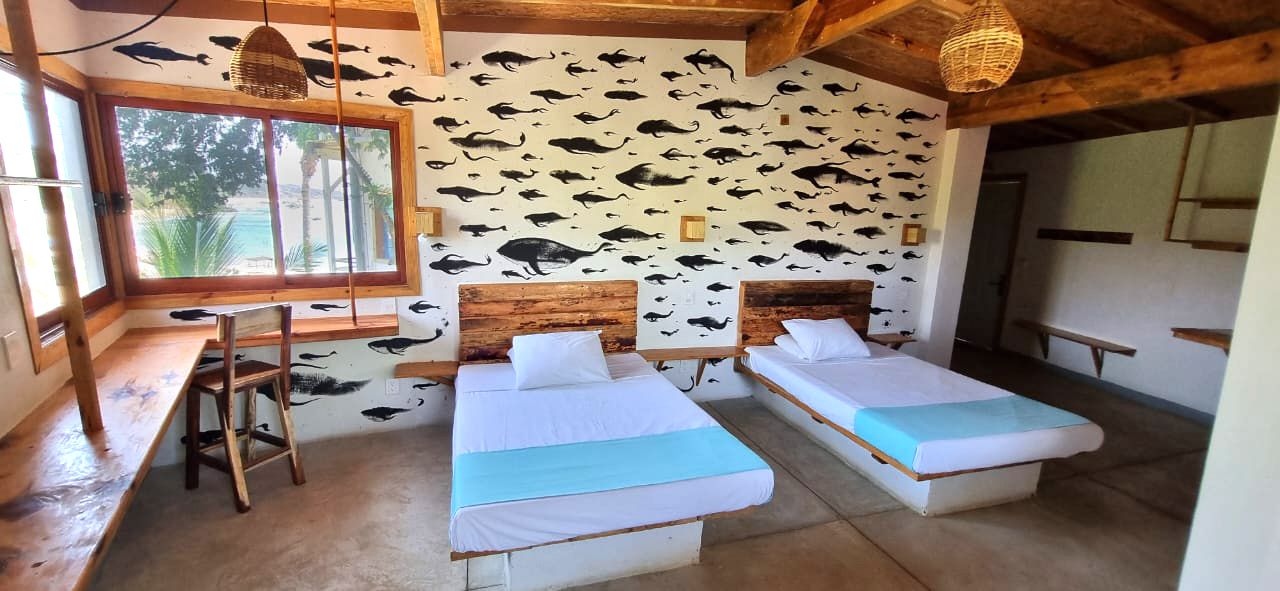 Dormitorio con dos camas y cabeceros de madera en posada del arquitecto en mazunte, oaxaca