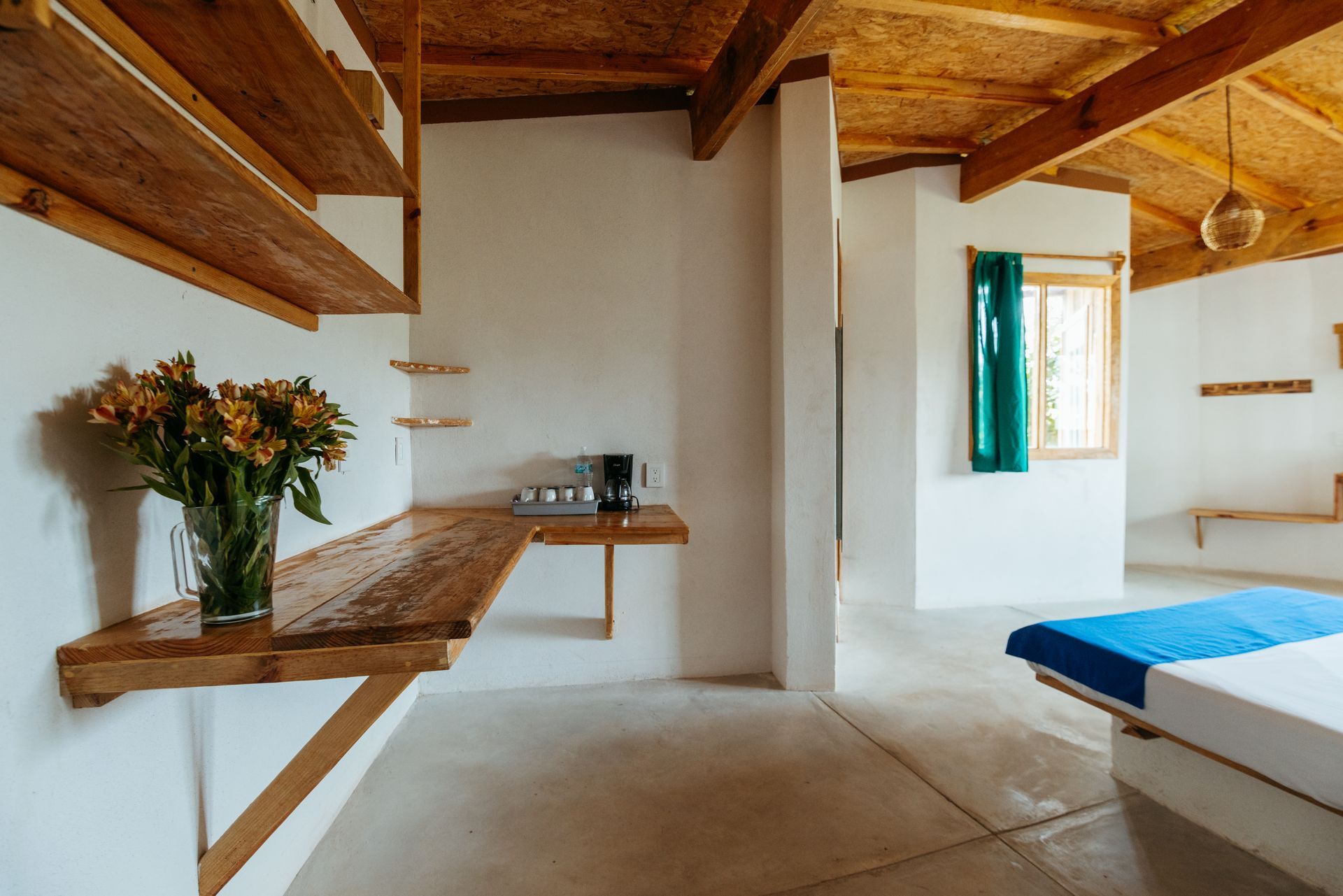 Habitación luminosa con paredes blancas, estanterías y techo de madera en posada del arquitecto en mazunte, oaxaca