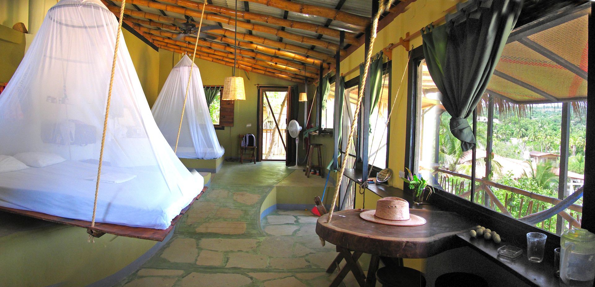 Interior de una habitación de estilo tropical con dos camas colgantes cubiertas con mosquiteros en posada del arquitecto