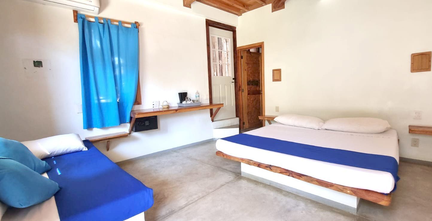Dormitorio con detalles azules: cama, sofá, cortina, escritorio en mazunte, oaxaca