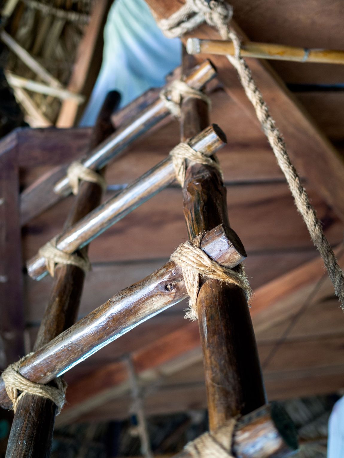 A close up of a wooden ladder with ropes attached to it.