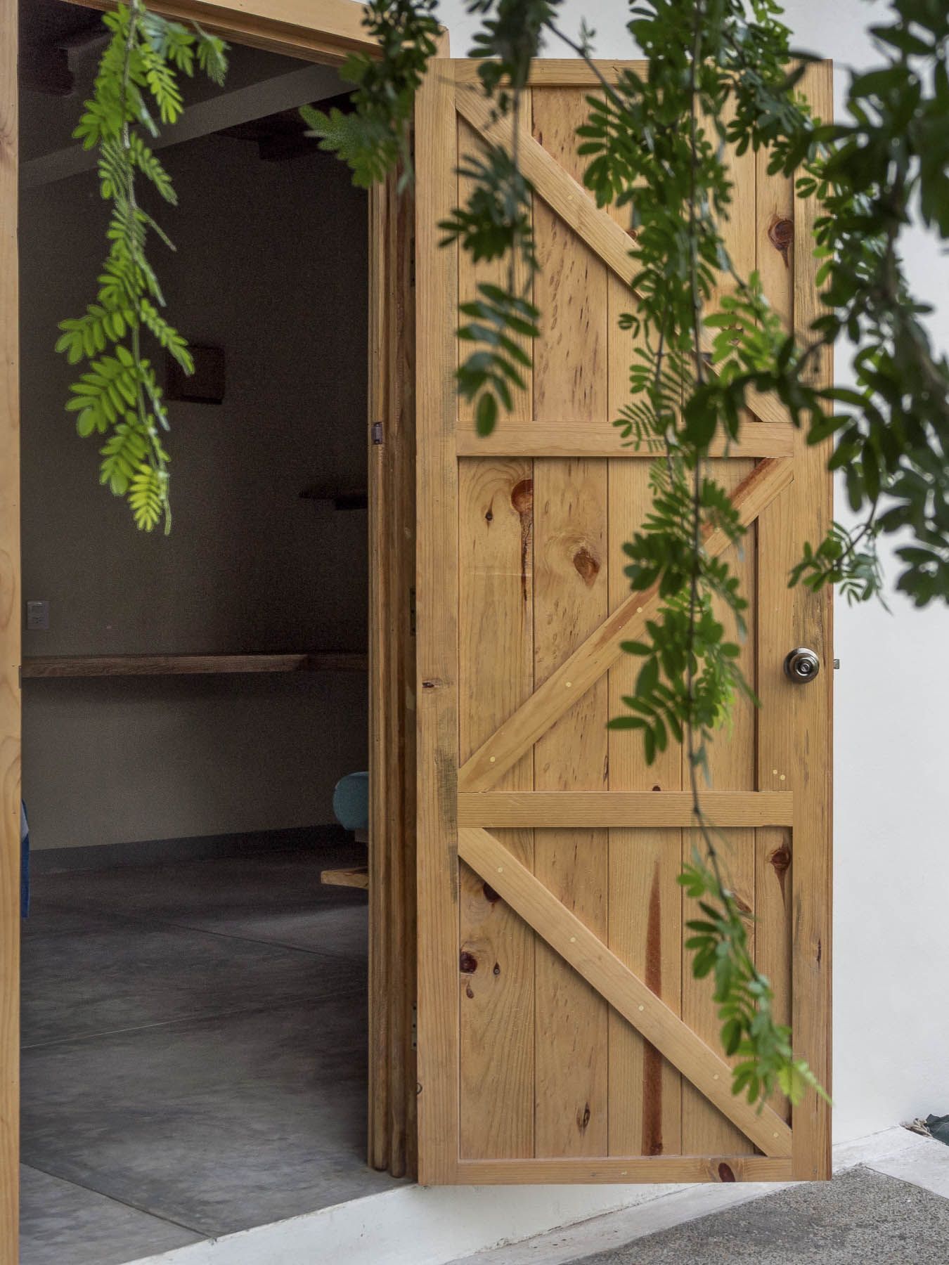 A wooden door with leaves hanging from it is open to a room.