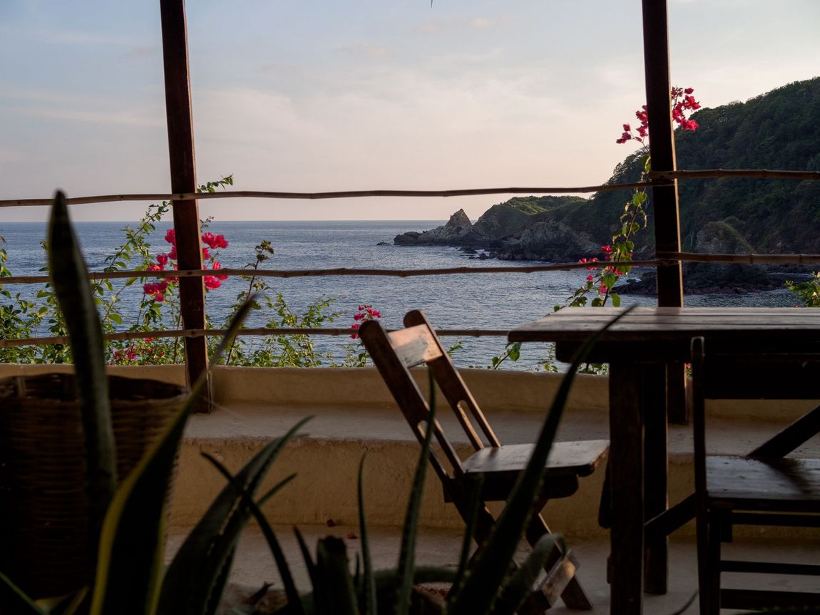 A view of the ocean from a balcony with a table and chairs