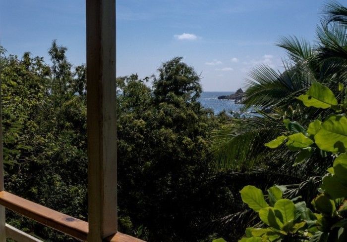 Vista del océano y la costa a través de los árboles desde un balcón de posada del arquitecto