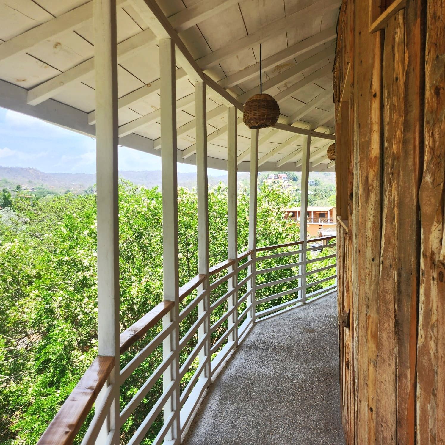 Balcón de madera con vistas a árboles verdes y montañas en mazunte, oaxaca