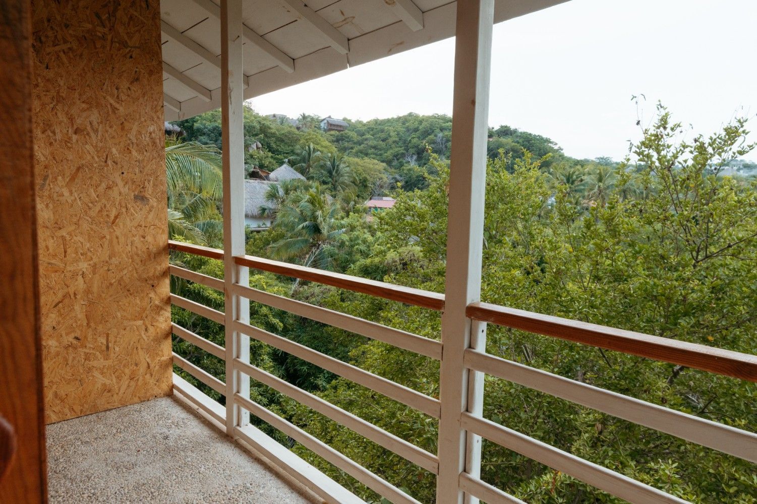 Balcón con vistas a frondosos árboles verdes en posada del arquitecto en mazunte, oaxaca