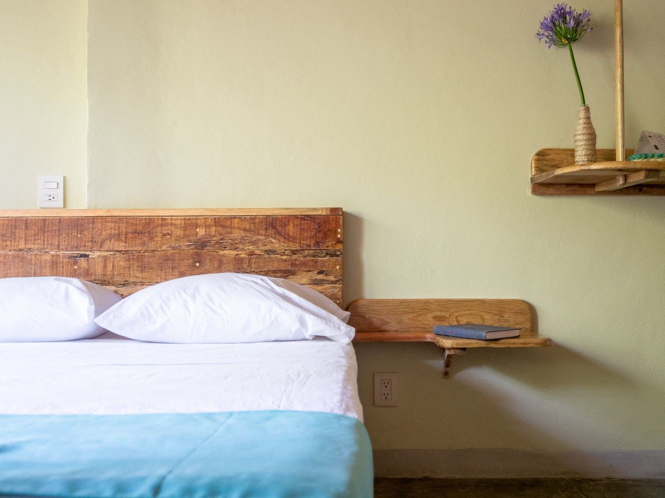 Dormitorio con cabecero y mesita de noche de madera en posada del arquitecto en mazunte, oaxaca