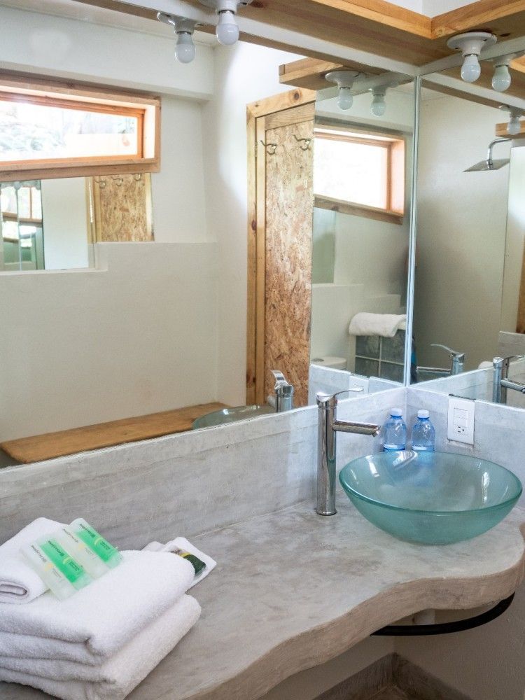 Baño con lavabo de cristal y encimera de piedra en posada del arquitecto en mazunte, oaxaca