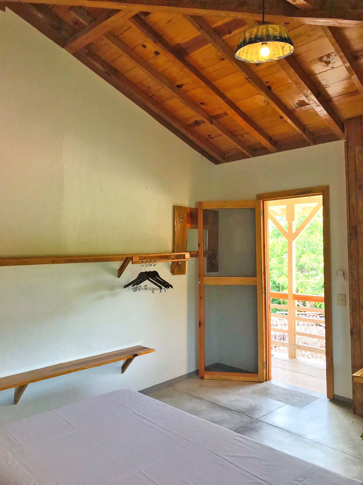 Dormitorio con techo de madera y puerta al balcón en posada del arquitecto en mazunte, oaxaca