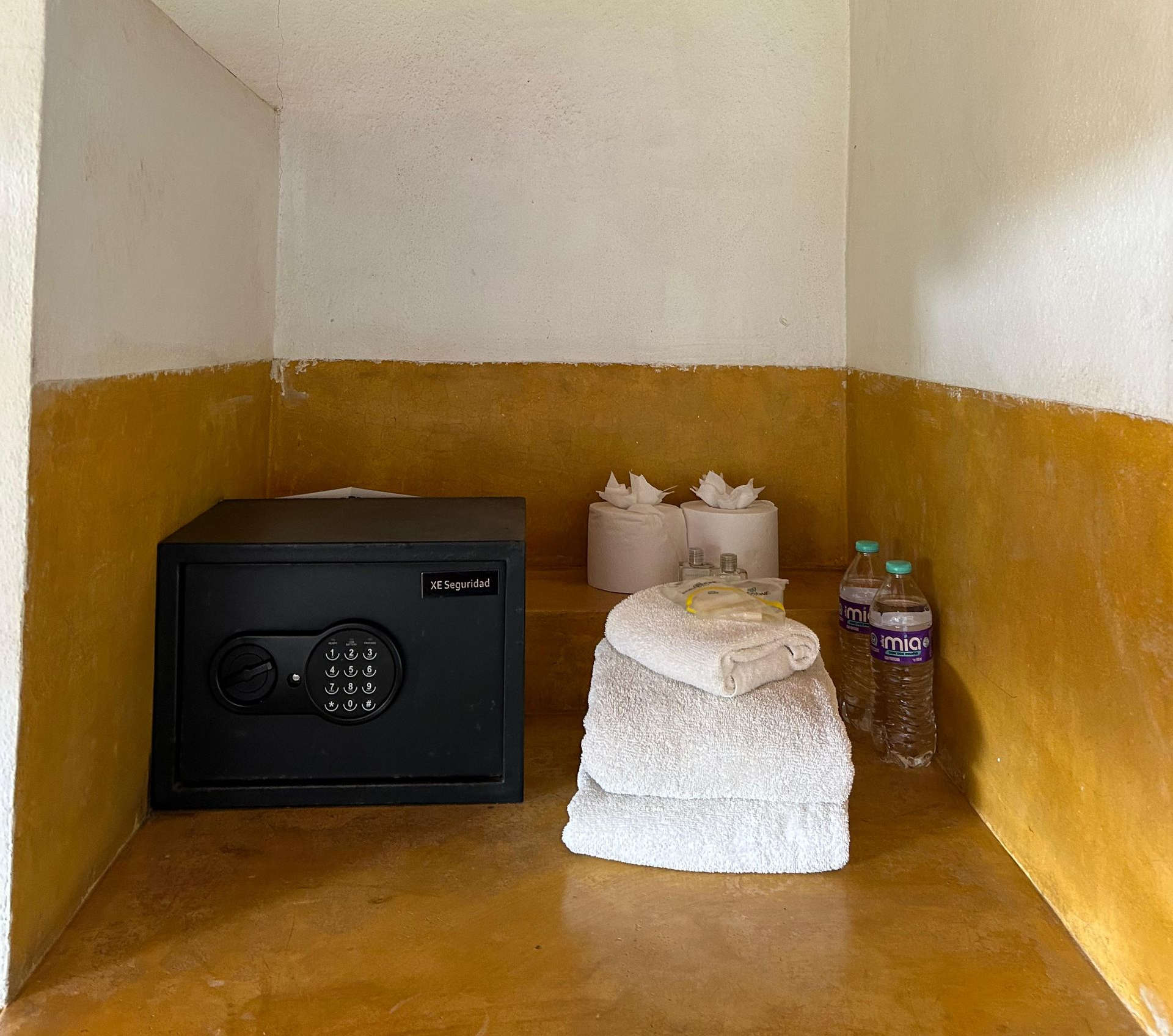 caja fuerte negra, toallas dobladas, pañuelos de papel y botellas de agua en posada del arquitecto en mazunte, oaxaca