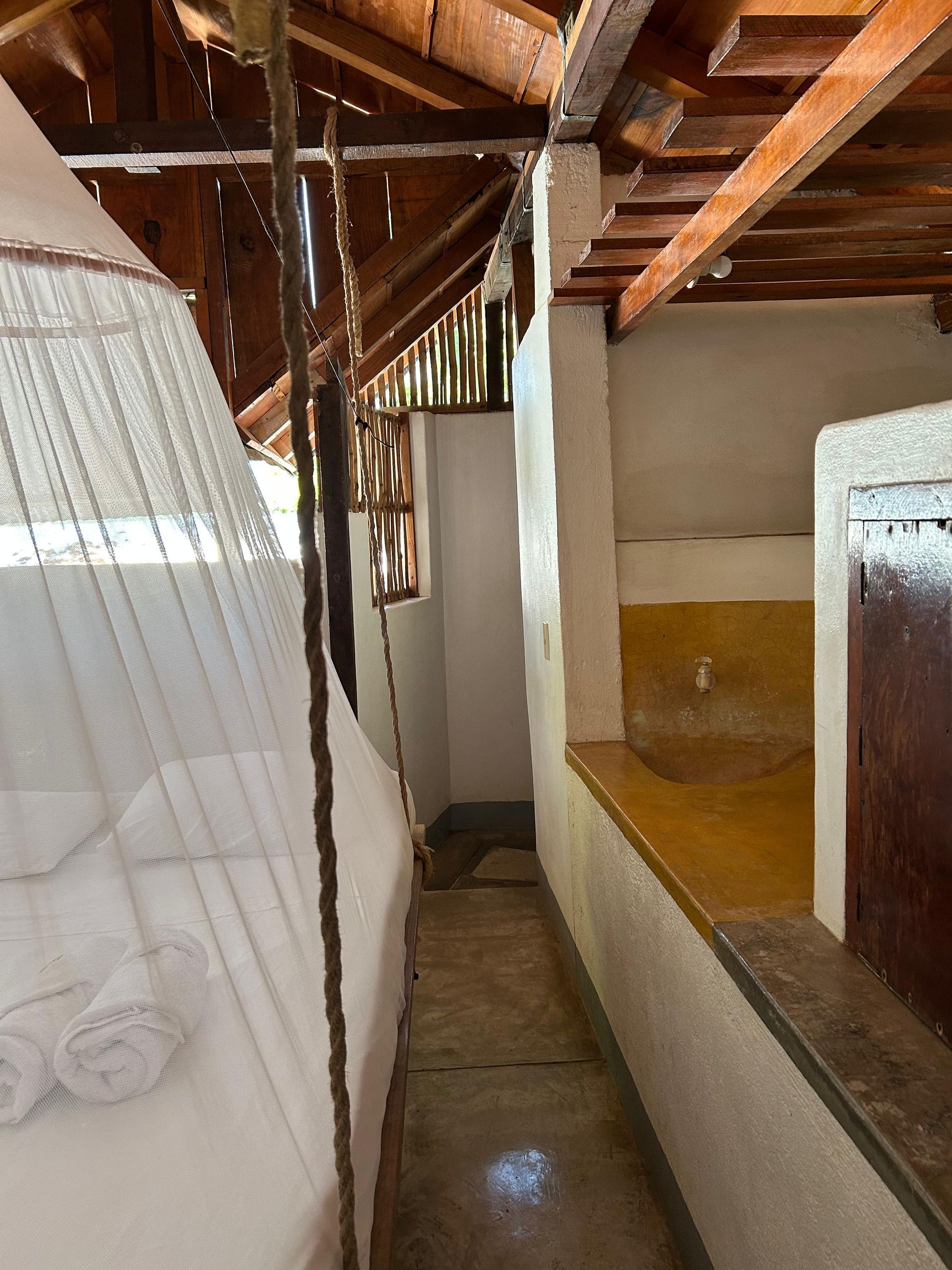 Habitación estrecha con cama y baño en posada del arquitecto en mazunte, oaxaca