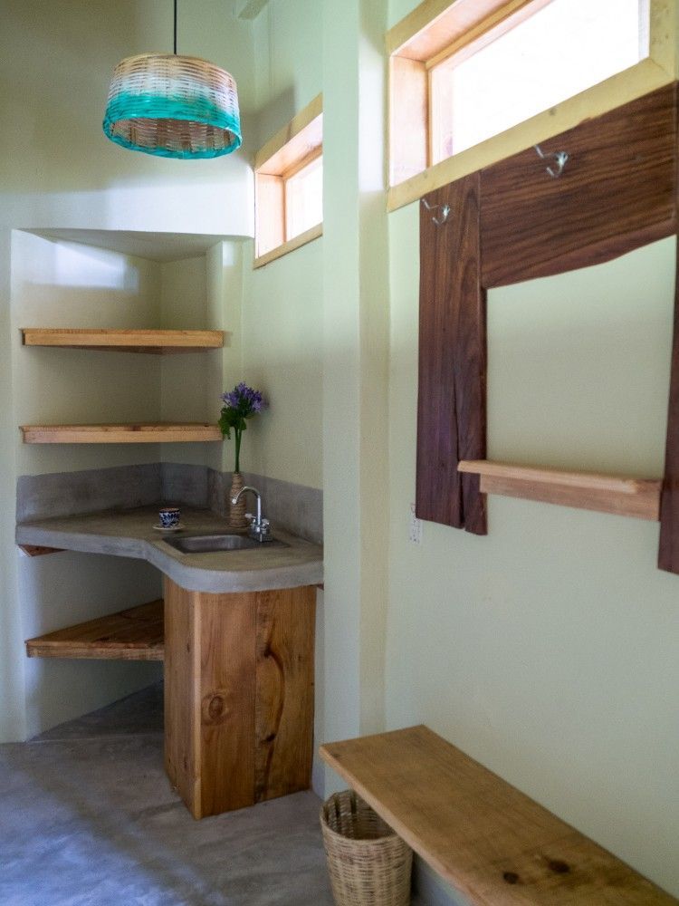 Rincón de baño con detalles de madera, estantes, lavabo y espejo rústico en posada del arquitecto en mazunte, oaxaca