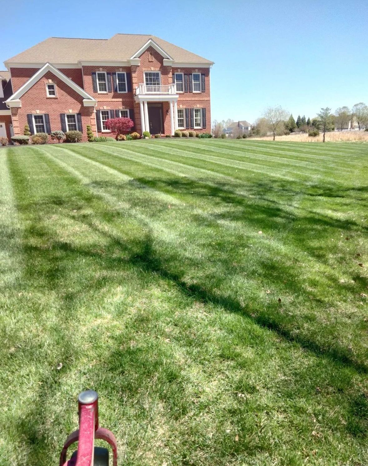 A large brick house with a lush green lawn in front of it.