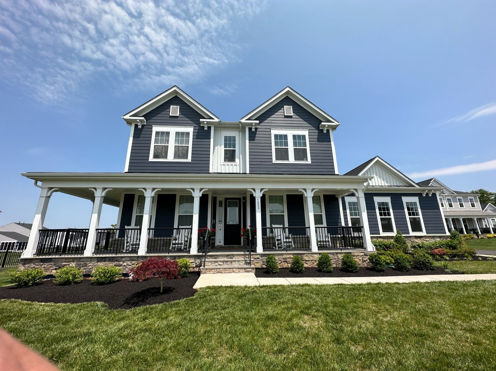 A large house with a large porch and a blue sky in the background.
