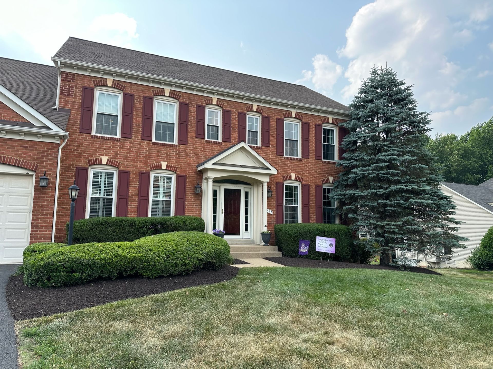 A large brick house with a large lawn in front of it.
