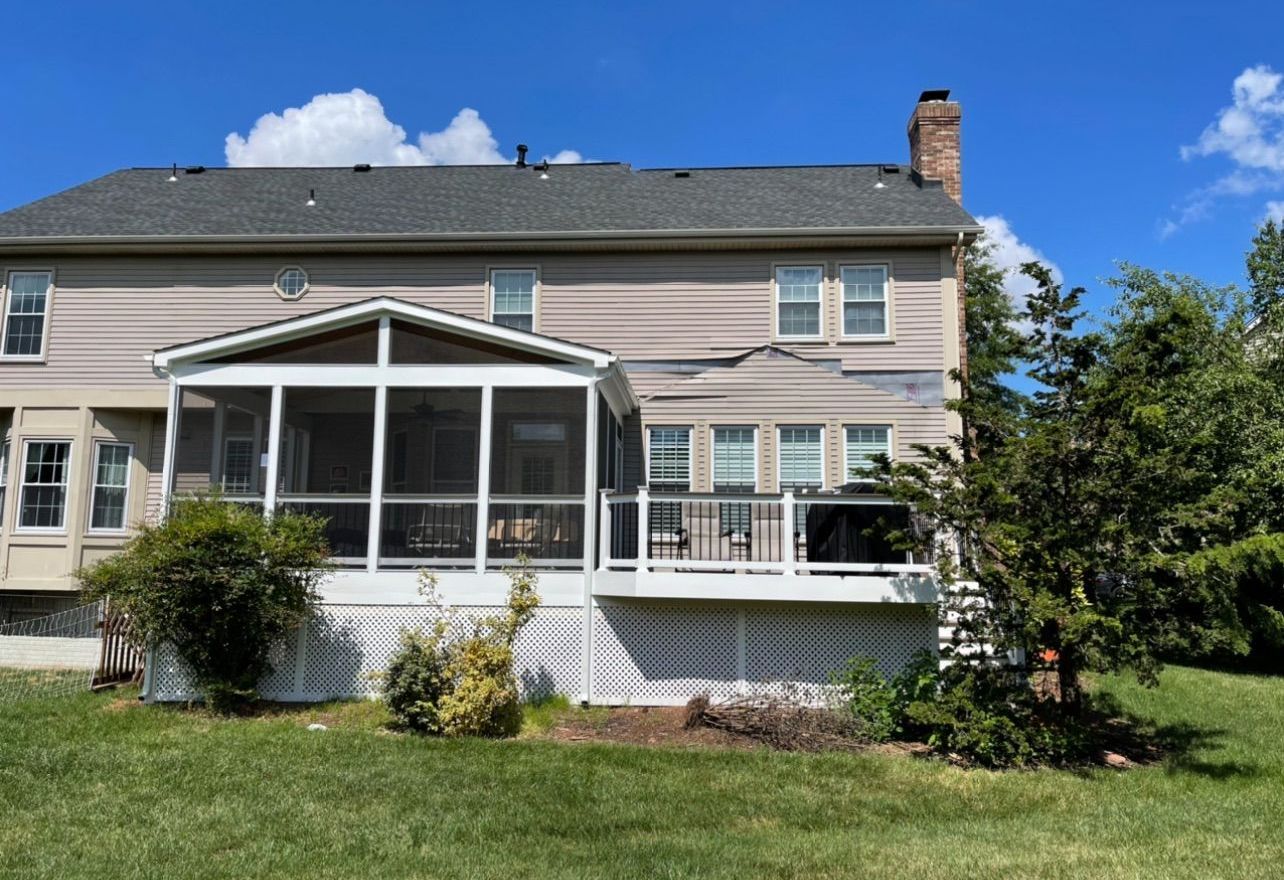 The back of a house with a screened in porch and a deck.